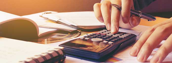Person Using Calculator To Determine How To Pay Tax Bill